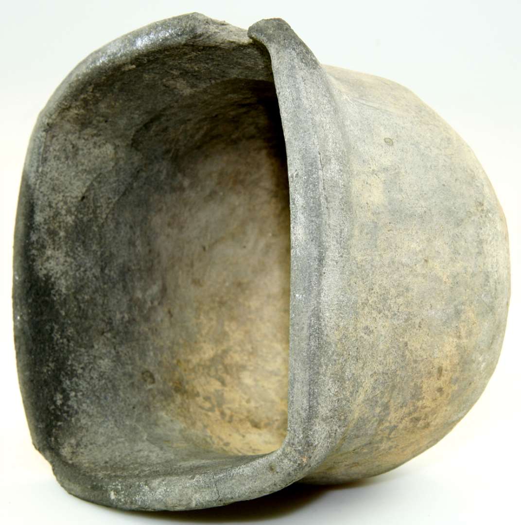 Pottekakkel af gr�br�ndt ler. Firkantet munding og kuppelformet bund; en enkelt flis sl�et af mundingsranden ved et hj�rne ellers fuldst�ndig bevaret. H�jde ca. 12,5 cm. Mundingen: ca. 14 x 14,5 cm.