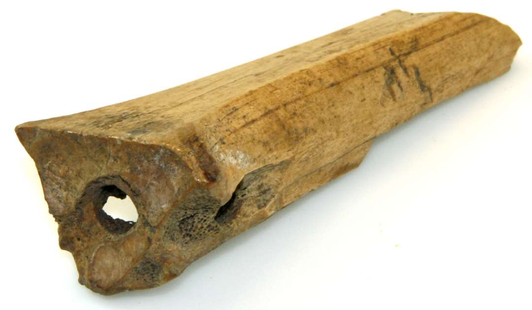 Fragment af Bensk�jte/isl�gger, lavet af R�rknogle; det er den bageste Ende af Sk�jten, som er bevaret. Huller til Sn�rebaand boret gennem Knoglen. L�ngde: 12,5 cm.