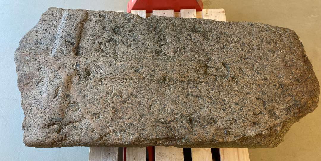 Gravsten af grovkornet, gr� granit med reliefhugget kors, �verste del af stenen mangler. H�jde: 154 cm. Bredde: 79 cm. Tykkelse:  20 cm.  