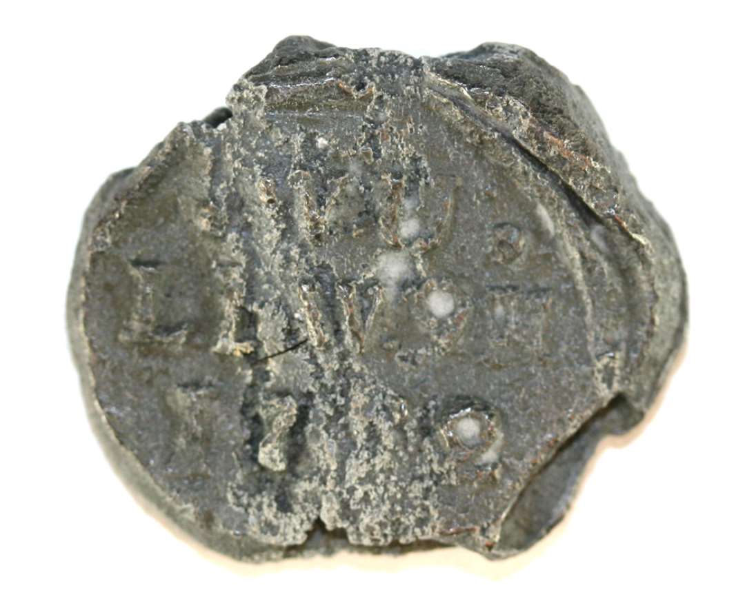 1 blyplombe. Omtrentlig cirkul�r form (diameter: ca. 2,6 cm.). Noget angrebet af pest. Pr�get p� begge sider: p� den ene: '.W.U./LI.W.9?/17(90?)' og p� den anden side formentlig russiske bogstaver i fire r�kker.