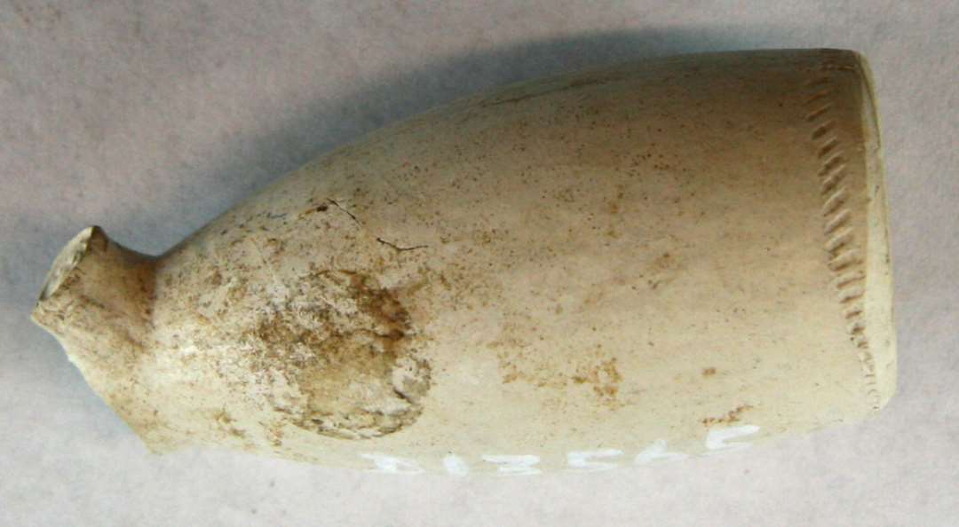 1 kridtpibehoved af glat langstrakt, konisk hv�lvet form, forsynet p� begge sider af h�len med et lille bitte v�benskjold i oph�jet relief, hvorover et S. P� h�lens cirkul�re underside findes et v�rkstedm�rke i oph�jet relief: en m�lkepige med et �g over skuldrene, hvorfra en spand h�nger ned ved hver side.