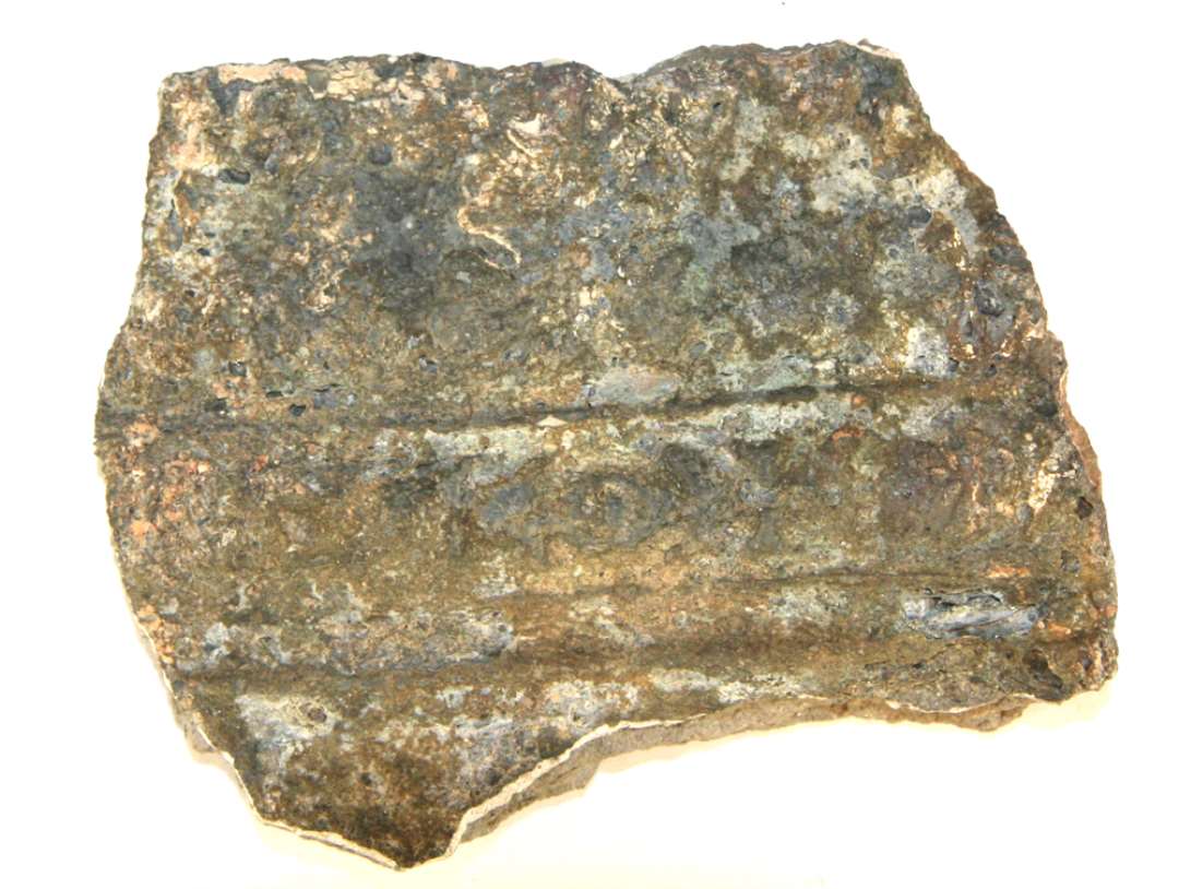 Fragment af st�rkt brandsintret gesimskakkel. P� forsiden ses en �ggestavsramme og vinkelret ud herfra sidestillede akantusblade i en t�t br�me. Glasuren er oprindelig gr�n, men fremtr�der nu helt gr�sintret og bl�ret. St�rste m�l: 9,5 cm.