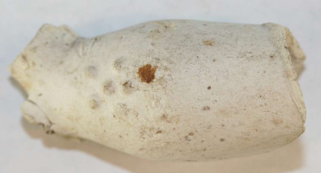 Hoved af kridtpibe. Stilken mangler. P� hovedets ene side 6 halvkugler, og p� den anden resterne af tilsvarende (formen �delagt). Lidt af siden mangler.�L�ngde: 3,6 cm.